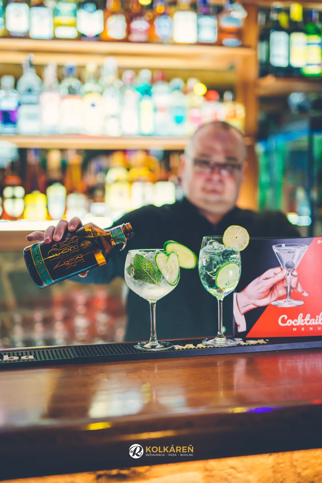 Barman przygotowuje gin z tonikiem, ogórkiem i miętą