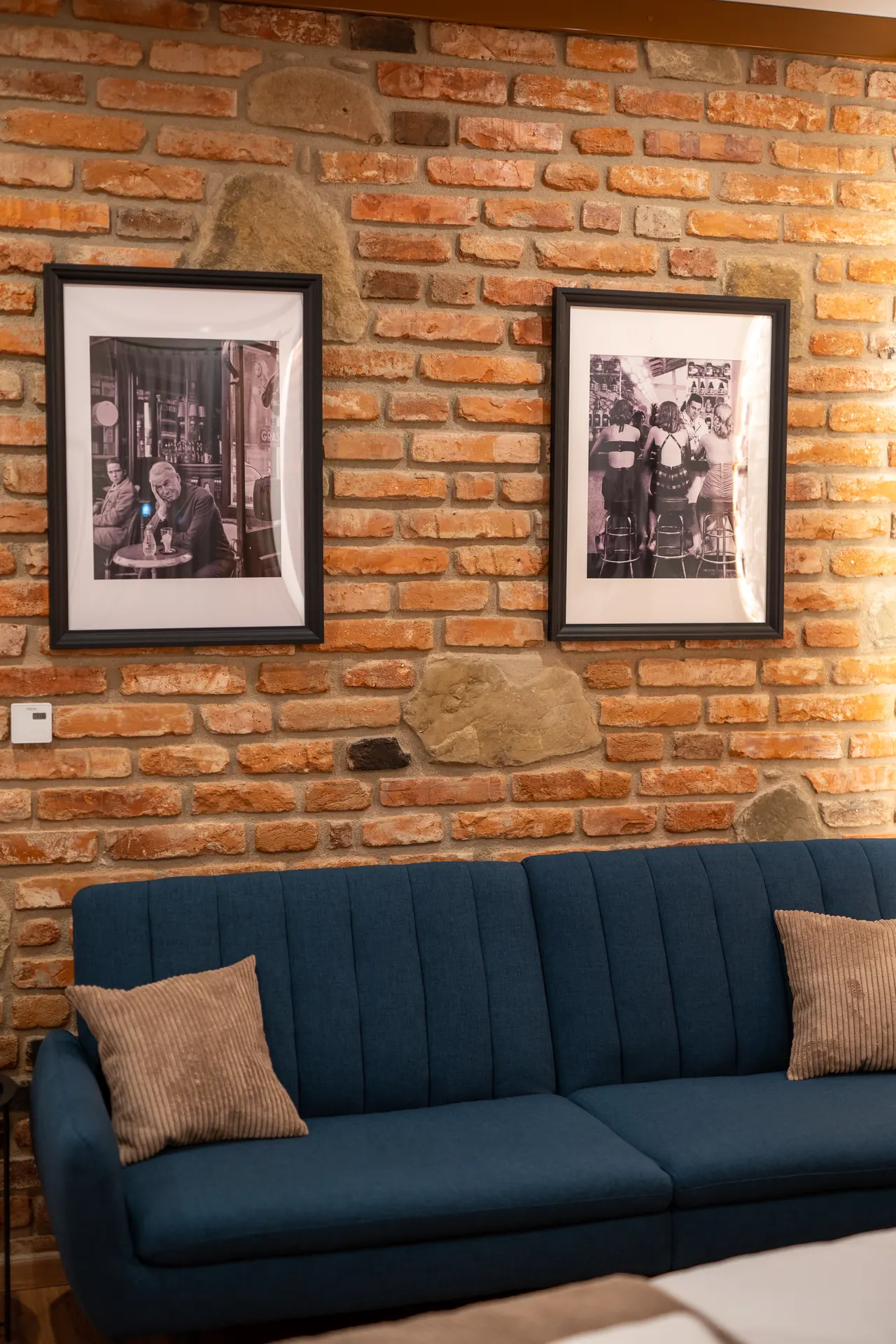 Modrá sedačka a fotografie na tehlovej stene v izbe Superior King